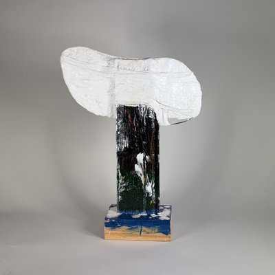 A white, roughly modelled head on a narrow dark painted support and a rectangular base.